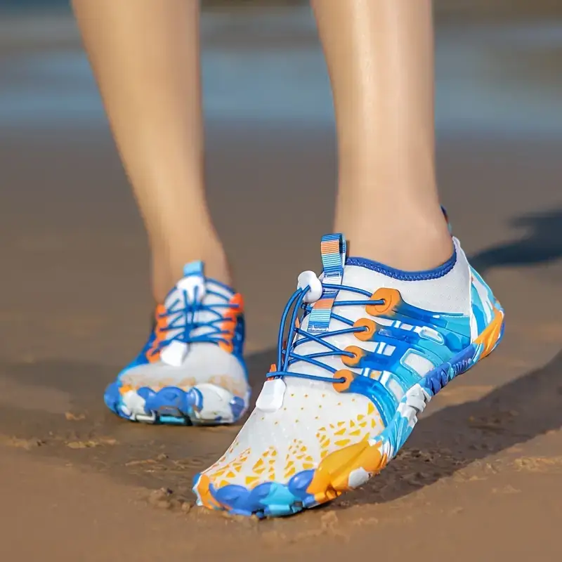 Bright blue, white and orange Racqua barefoot water shoes with quick-pull laces on wet beach sand